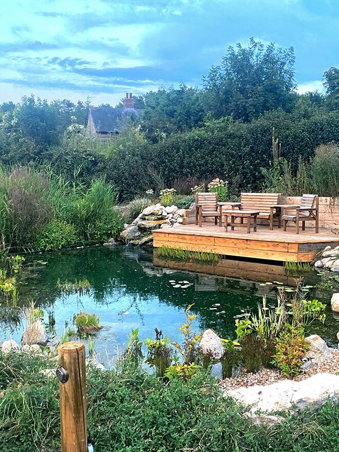Natural pond with a floating timber deck, table and chairs